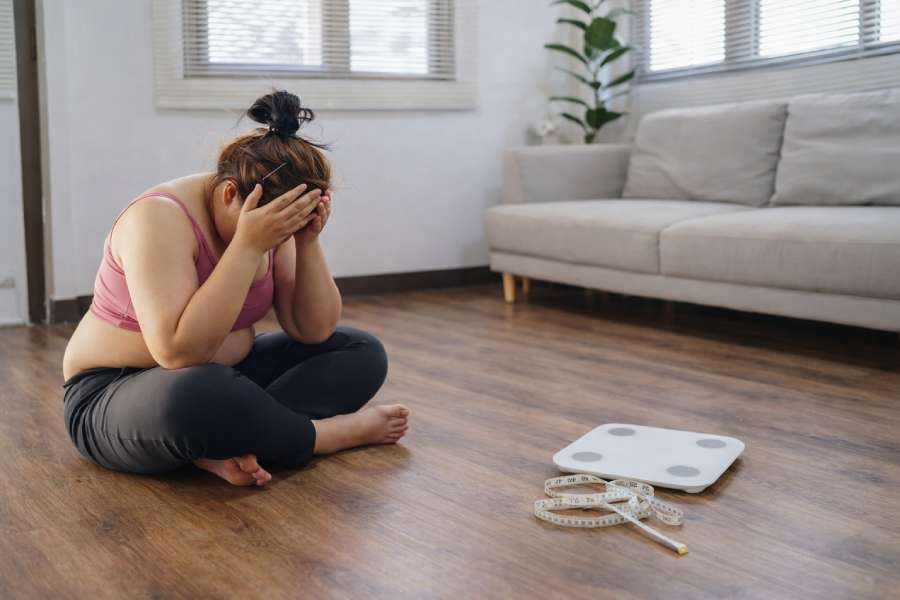 Frau blickt frustriert auf eine Waage